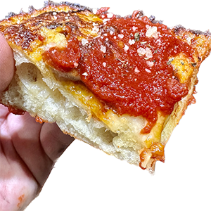 Detroit Pizza Slice with a rich tomato sauce and thick fluffy airy crust.